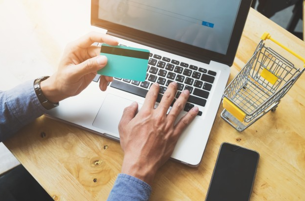 imagem ampliada de pessoa sentada à mesa com cartão em uma mão mexendo no computador